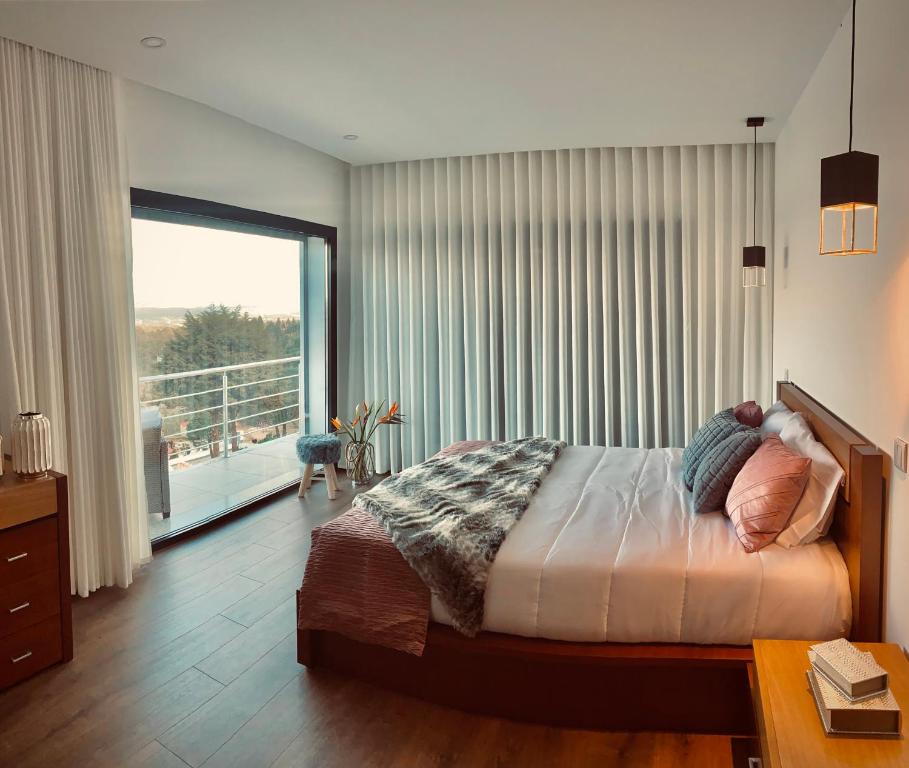 um quarto com uma cama e uma grande janela em Quinta do Cascalheiro em Leiria