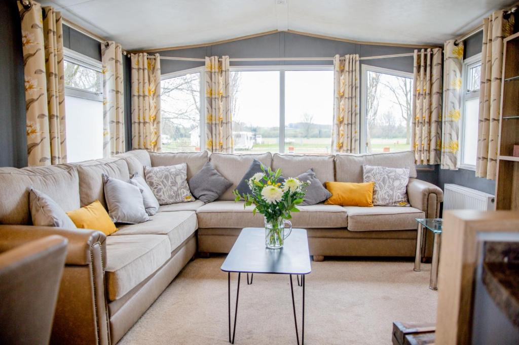 a living room with a couch and a table with a vase of flowers at Billing Aquadrome Northampton lovely Waterside 2 Bedroom static holiday home Shemar in Northampton