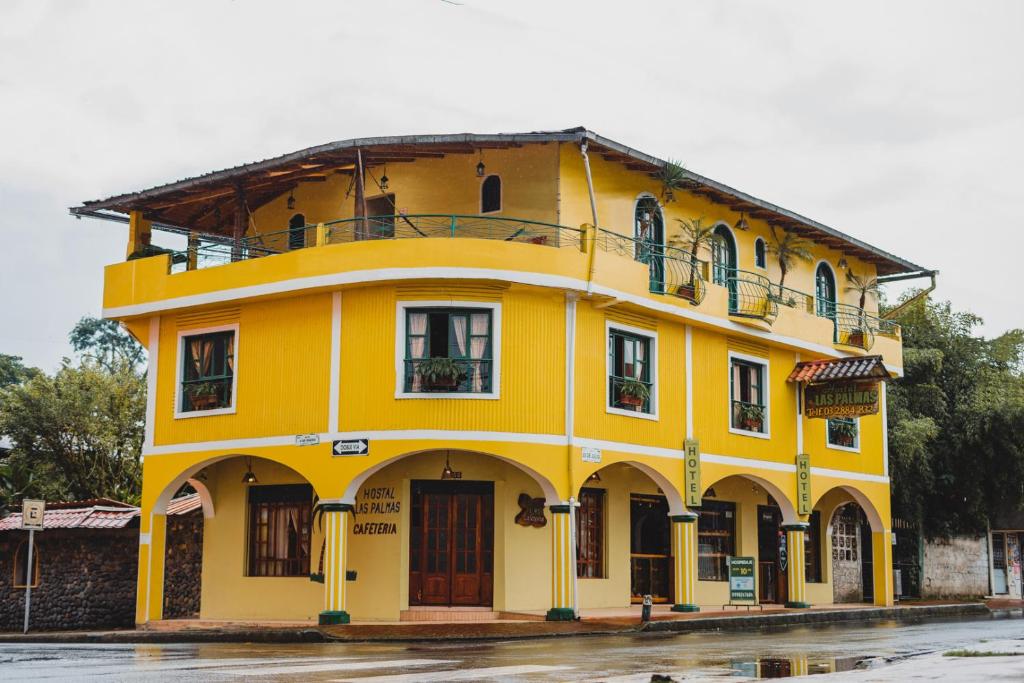 un edificio amarillo sentado al lado de una calle en Hostal Las Palmas, en Puyo