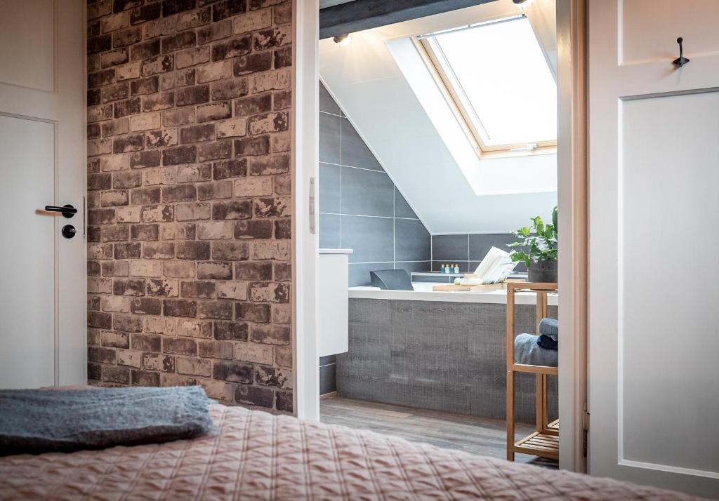 een slaapkamer met een bakstenen muur en een bad bij 't Tuinhoes in Reuver