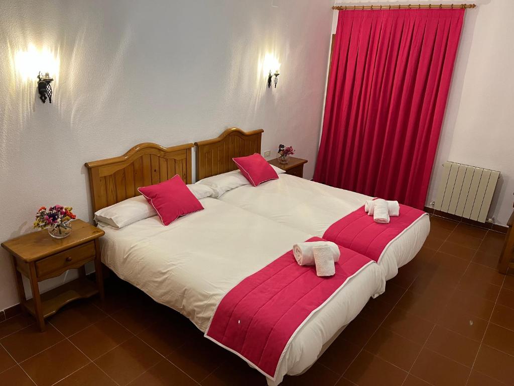 a bedroom with two beds with red curtains at Hostal Ciudad Encantada in Cuenca
