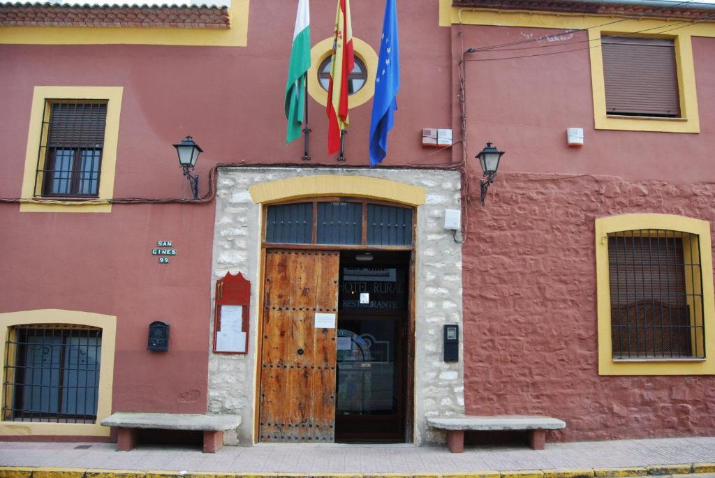 a building with two benches in front of a door at Alojamiento Rural La Fabrica in Sabiote