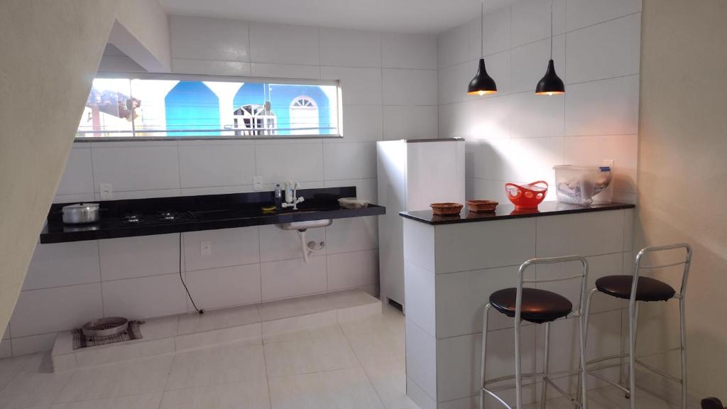 eine Küche mit einer Spüle und 2 Hockern in der Unterkunft Praia de Setiba - Kitnet in Guarapari