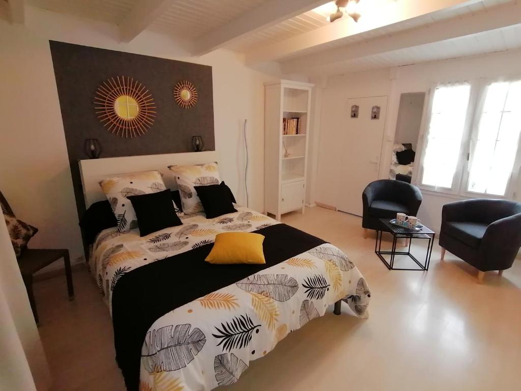 een slaapkamer met een groot bed en een stoel bij Le Cottage in Rochefort