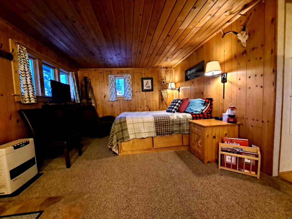 - une chambre avec un lit dans une pièce en bois dans l'établissement Northwoods Cottage Bed and Breakfast, à Fairbanks