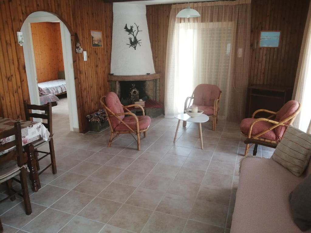 salon z różowymi krzesłami i kominkiem w obiekcie Villa Sunrise Seaside w Kalamácie