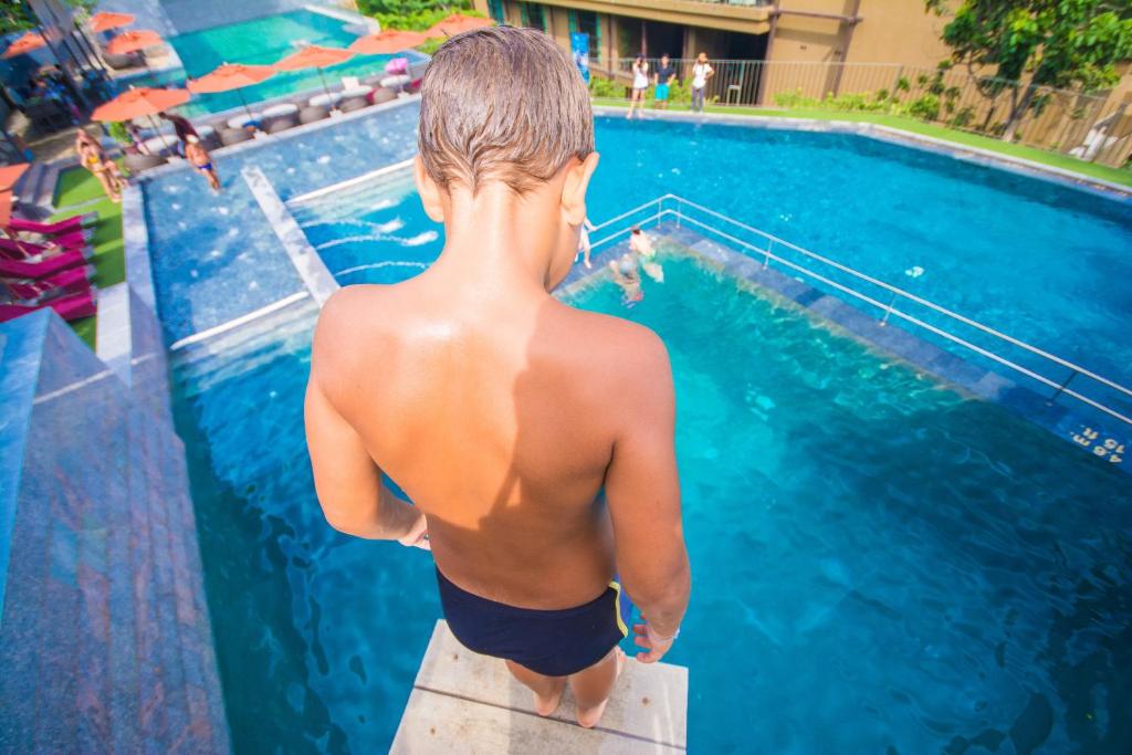 a young boy standing next to a swimming pool at Sunsuri Phuket - SHA Plus in Nai Harn Beach