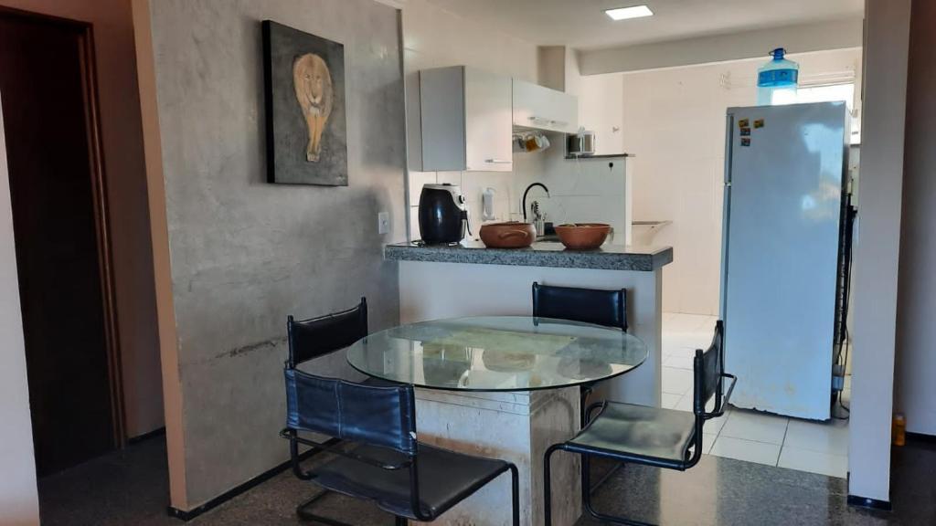 a kitchen with a glass table and chairs in a kitchen at APARTAMENTO EM NATAL II in Natal