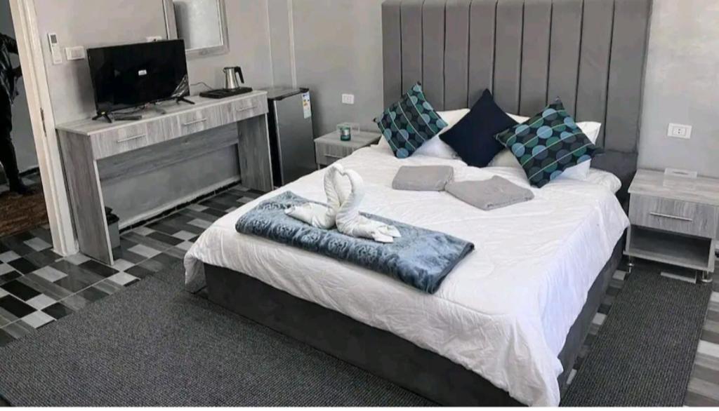 - une chambre avec un grand lit blanc et une télévision dans l'établissement Petra Pillars Hostel, à Wadi Musa