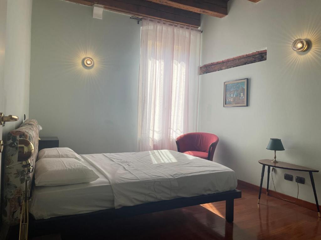a bedroom with a bed and a chair and a window at Loft Ponte Pietra in Verona