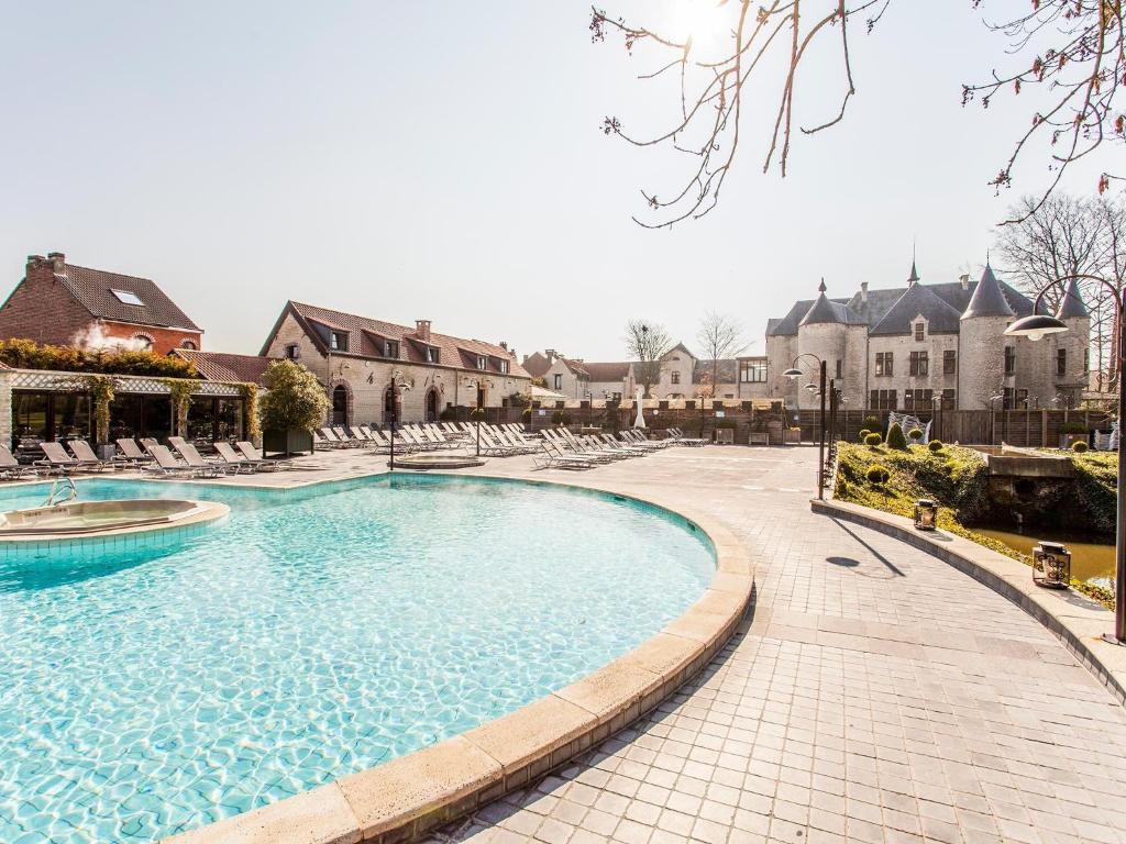 una gran piscina con sillas en un patio en Thermae Boetfort Hotel, en Steenokkerzeel