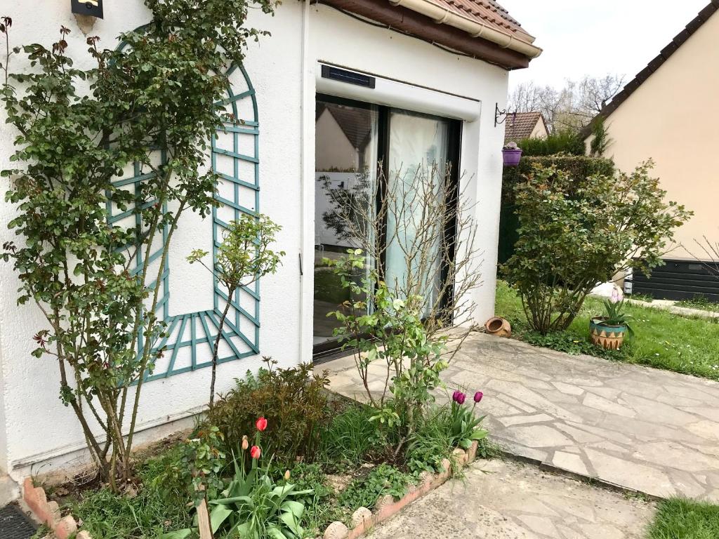 a white house with a blue door and some flowers at Parisian Forest in Cesson