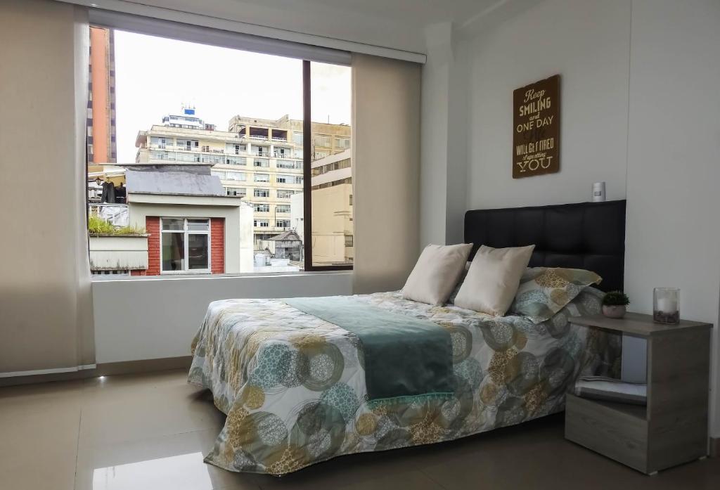 a bedroom with a bed and a large window at Hermoso Apartamento Central in Pereira