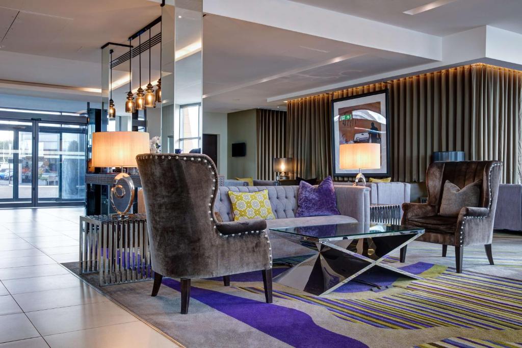 a lobby with a couch and a table and chairs at Radisson Blu Waterfront Hotel, Jersey in Saint Helier Jersey
