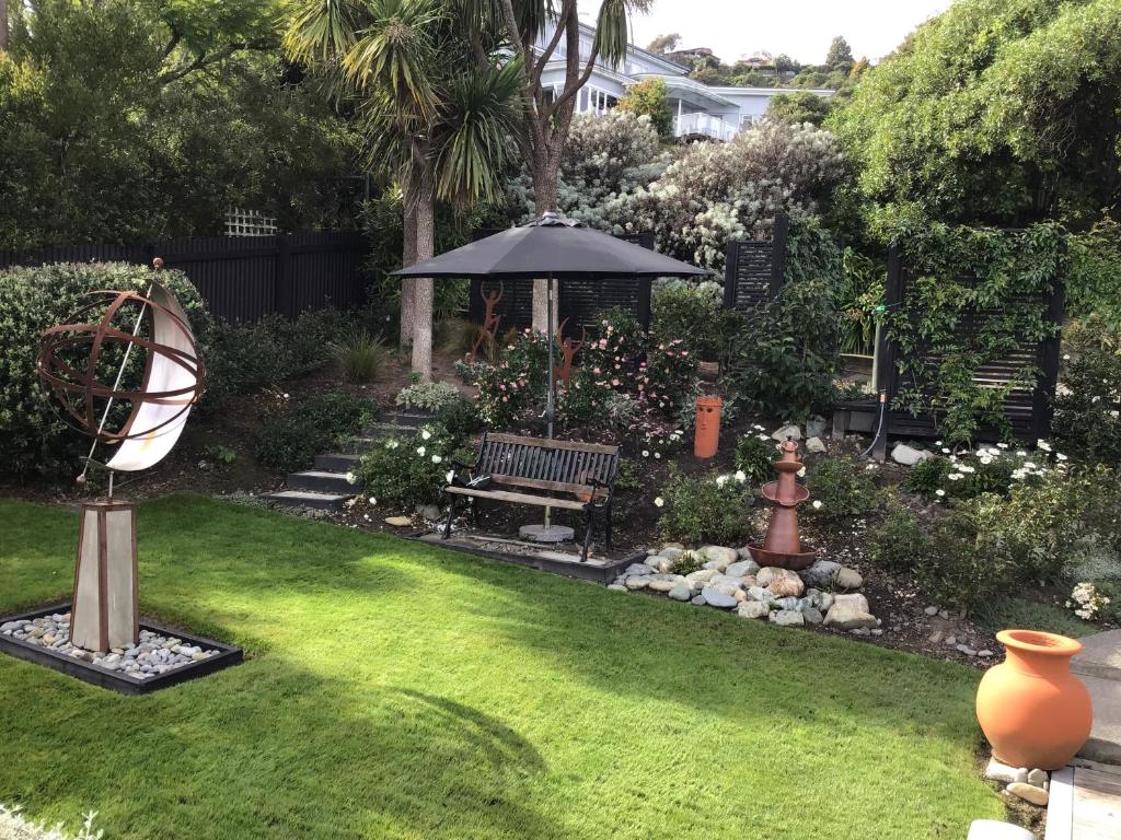 a garden with a bench and an umbrella at Apartment on Stansell in Nelson