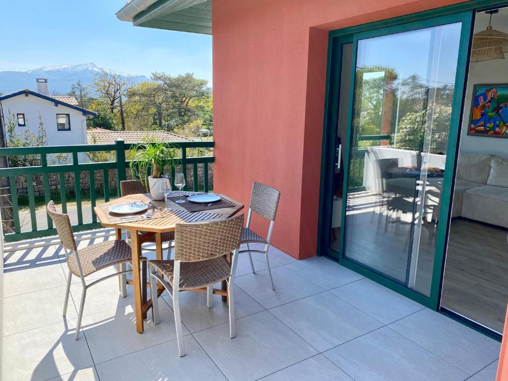 una mesa y sillas en un patio con balcón en Superbe appartement, grande terrasse vue mer et montagne, en San Juan de Luz