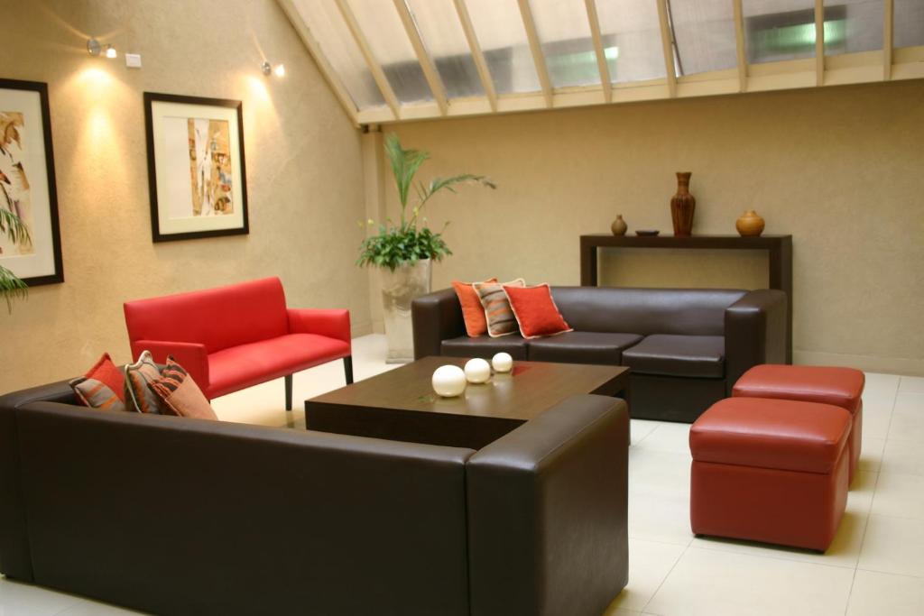 a living room with a black couch and red chairs at Hotel Cordon Del Plata in Mendoza