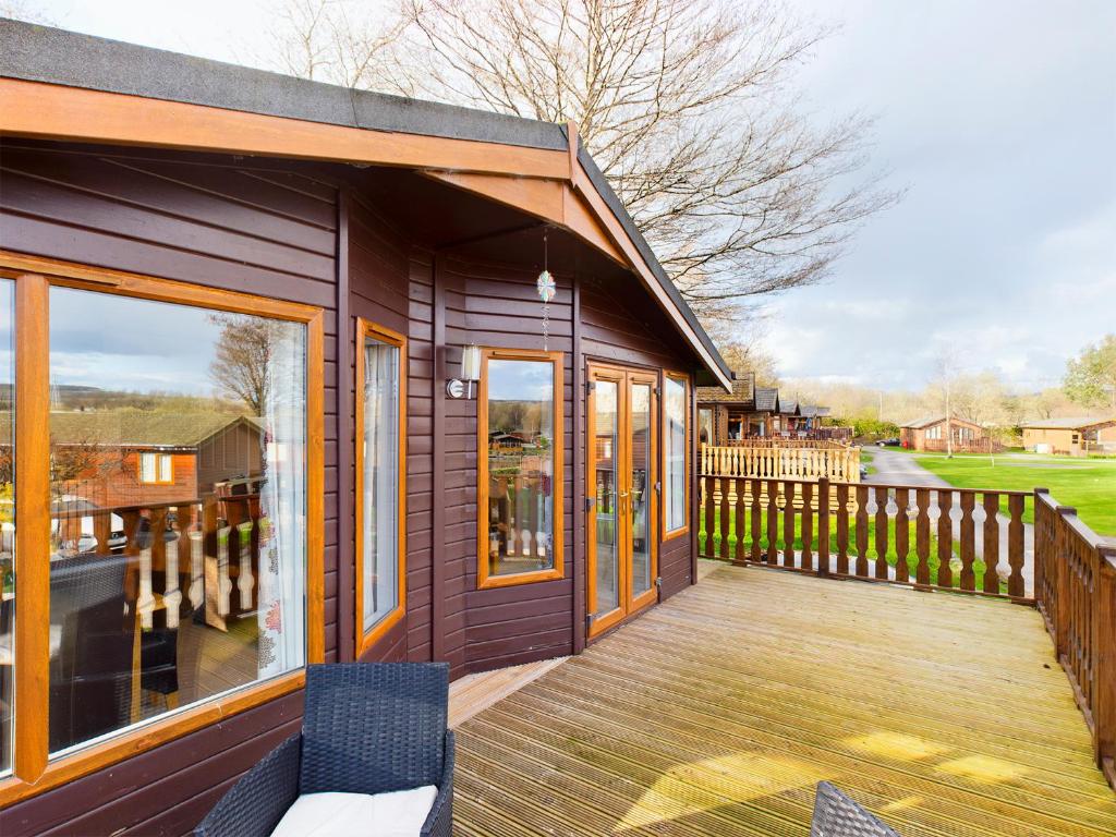 a house with a wooden deck with two chairs at 3 Bedroom Lakeview Lodge - Ensuite & Balcony Deck in Carnforth