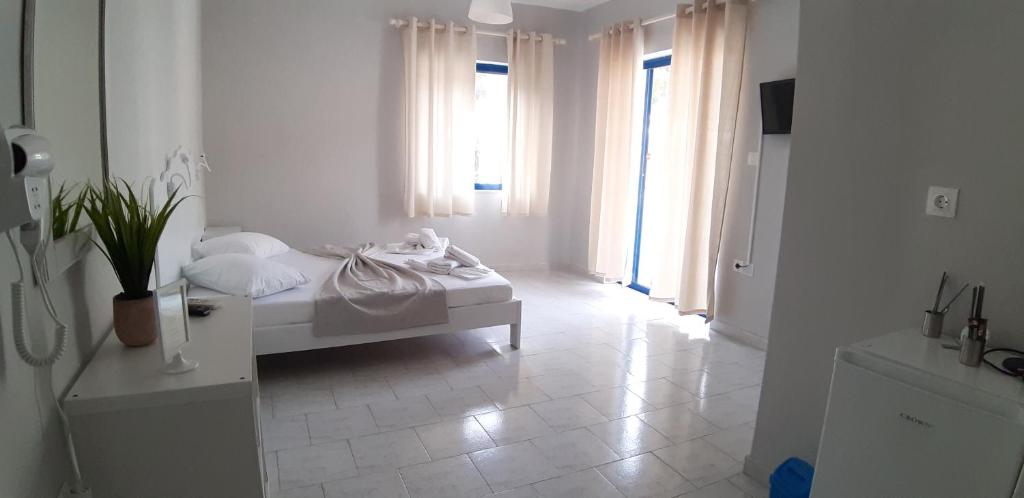 ein weißes Zimmer mit einem Bett und einem Fenster in der Unterkunft blue & white askeli studios in Poros