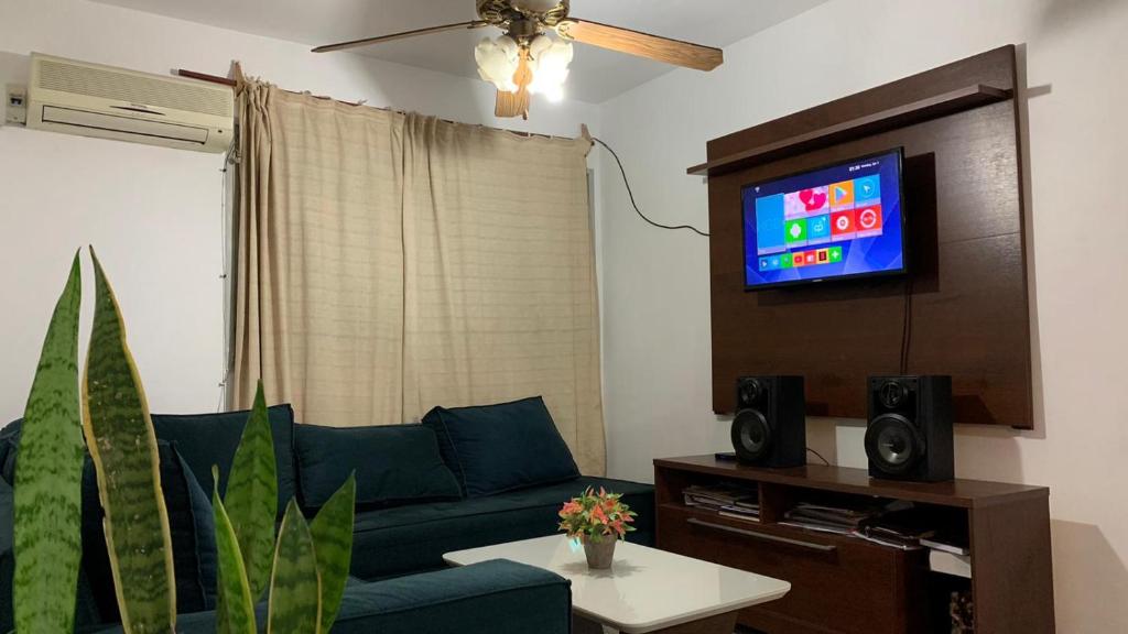 ein Wohnzimmer mit einem blauen Sofa und einem TV in der Unterkunft Amplio apartamento c/ todos los servicios y garage in Salto