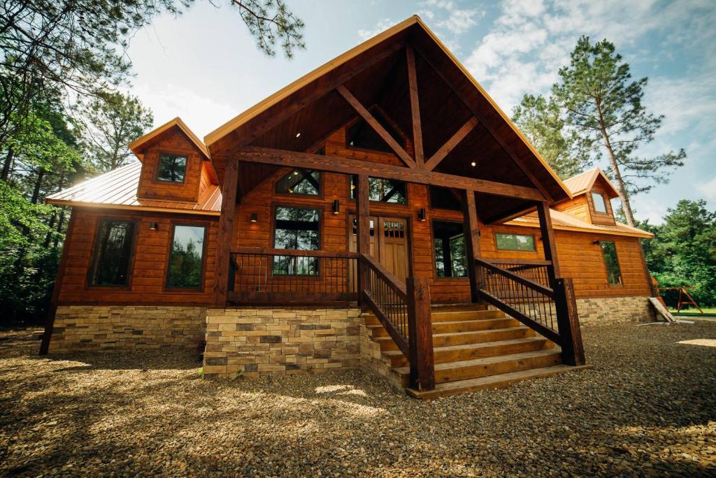 a large wooden house with stairs in front of it at Came Here to Forget Cabin in Broken Bow