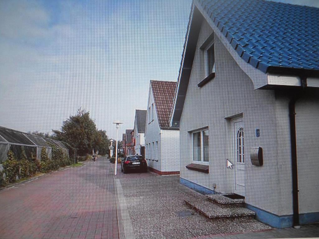 una calle con dos edificios blancos y un coche aparcado en la calle en Haus Seestern, en Büsum