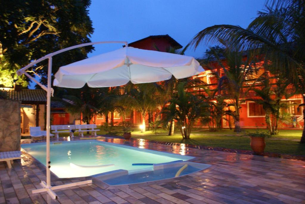 an umbrella sitting next to a swimming pool at Pousada Tempo Rei in Boicucanga