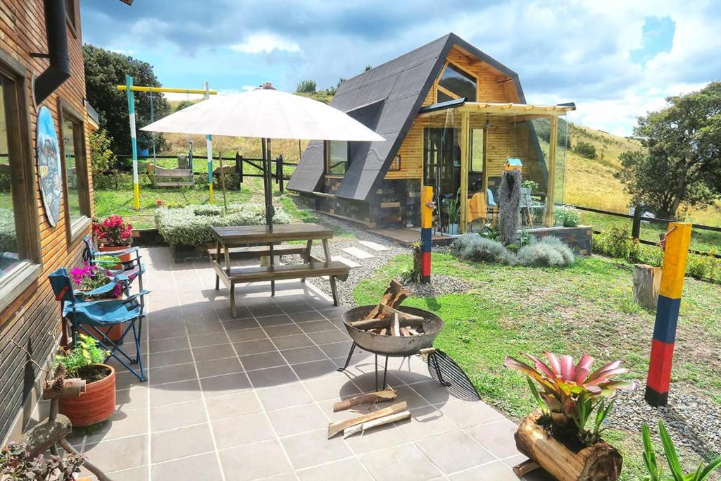 eine Terrasse mit einem Tisch und einem Sonnenschirm in der Unterkunft Refugio entre el cielo in Guatavita