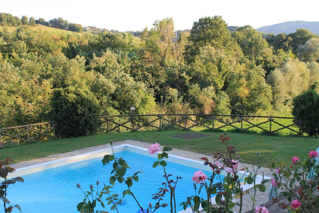 una piscina en un patio con árboles y flores en Fattoria di Rigone, en Coltavolino