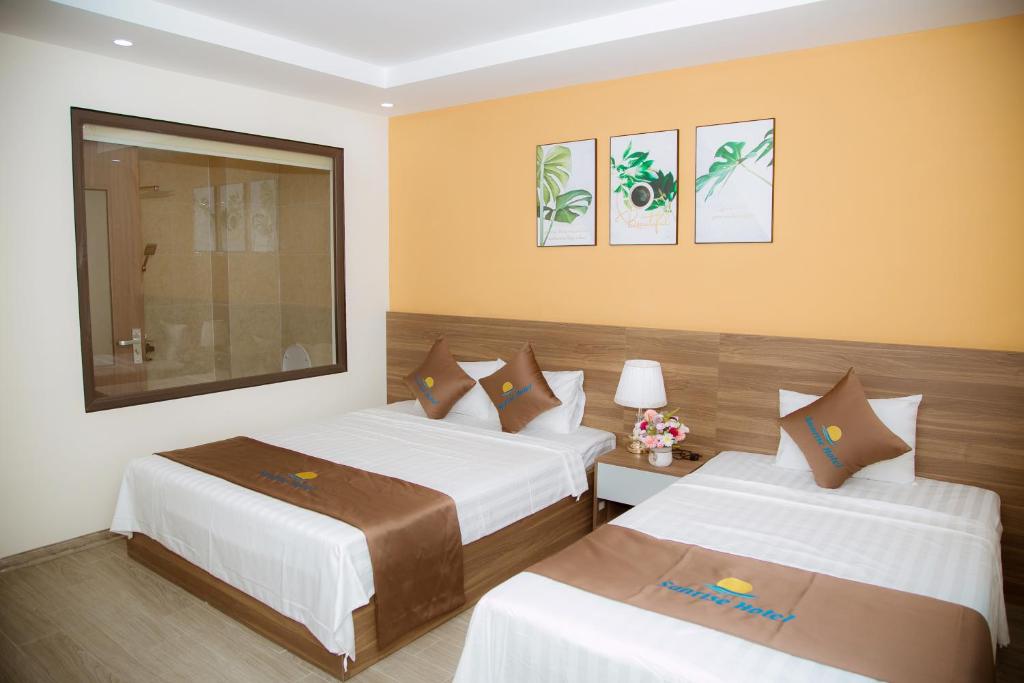 two beds in a hotel room with yellow walls at Sunrise Hải Tiến in Thanh Hóa