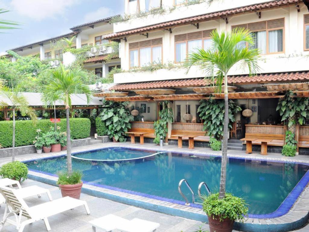 een zwembad voor een gebouw met palmbomen bij Mutiara Hotel and Convention in Bandung