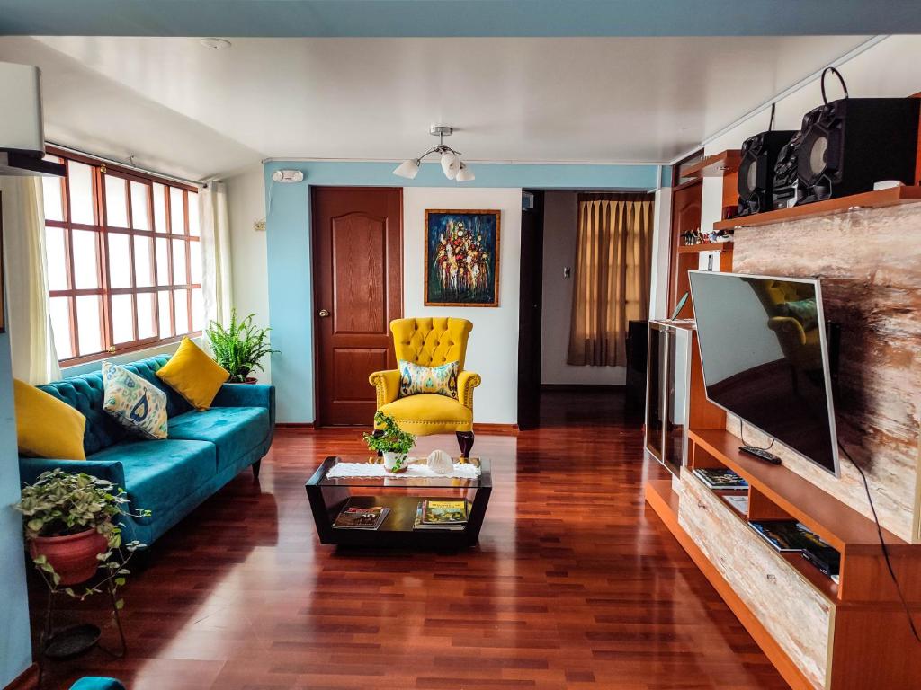 uma sala de estar com um sofá azul e uma televisão em Casa de Laura em Cusco