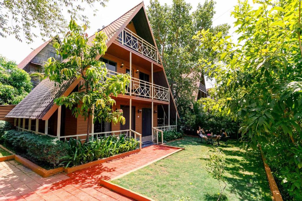 an exterior view of a house with a yard at StayVista at Wooden House with Jacuzzi in Wada