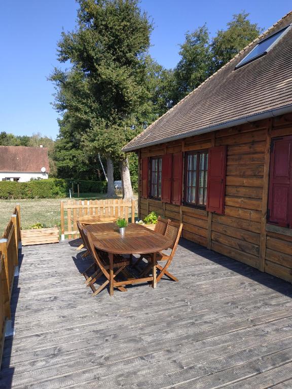 une terrasse en bois avec une table et des chaises devant une cabine dans l'établissement Le pâtureau d'en haut, à Gièvres
