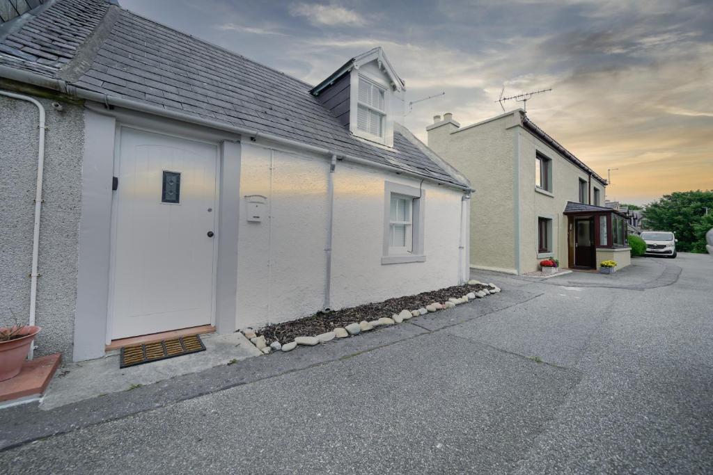 a white house with a white door on a street at The Wee House by the Sea in Balintore