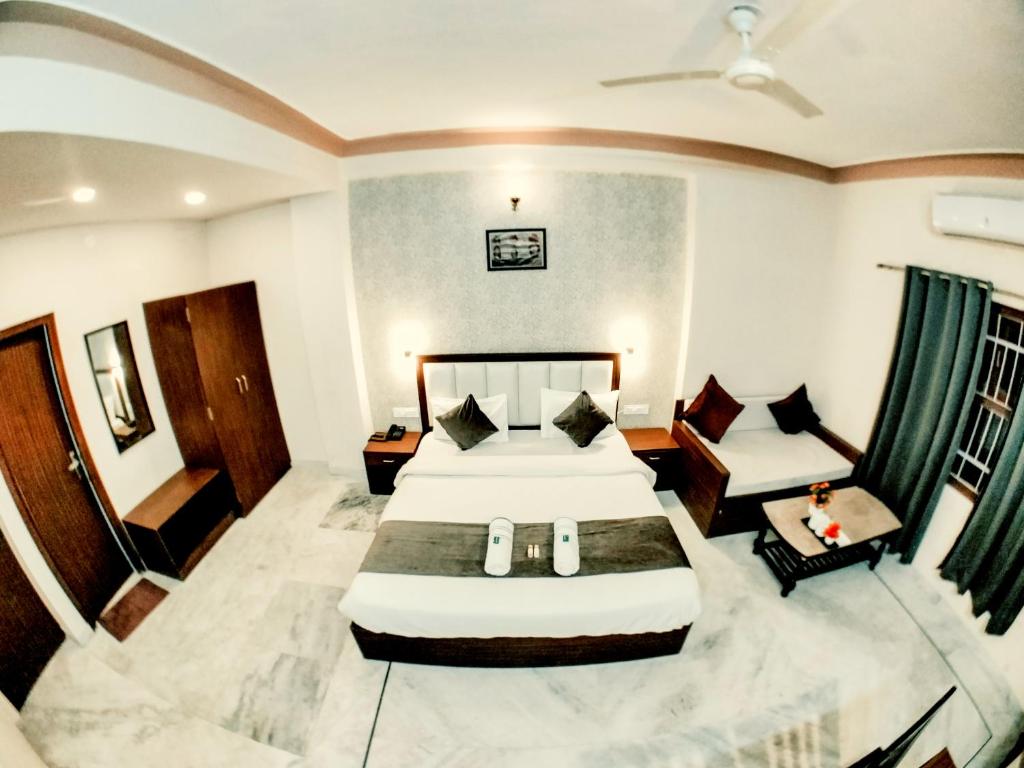 a hotel room with two beds and a couch at Tripli Udaipur in Udaipur