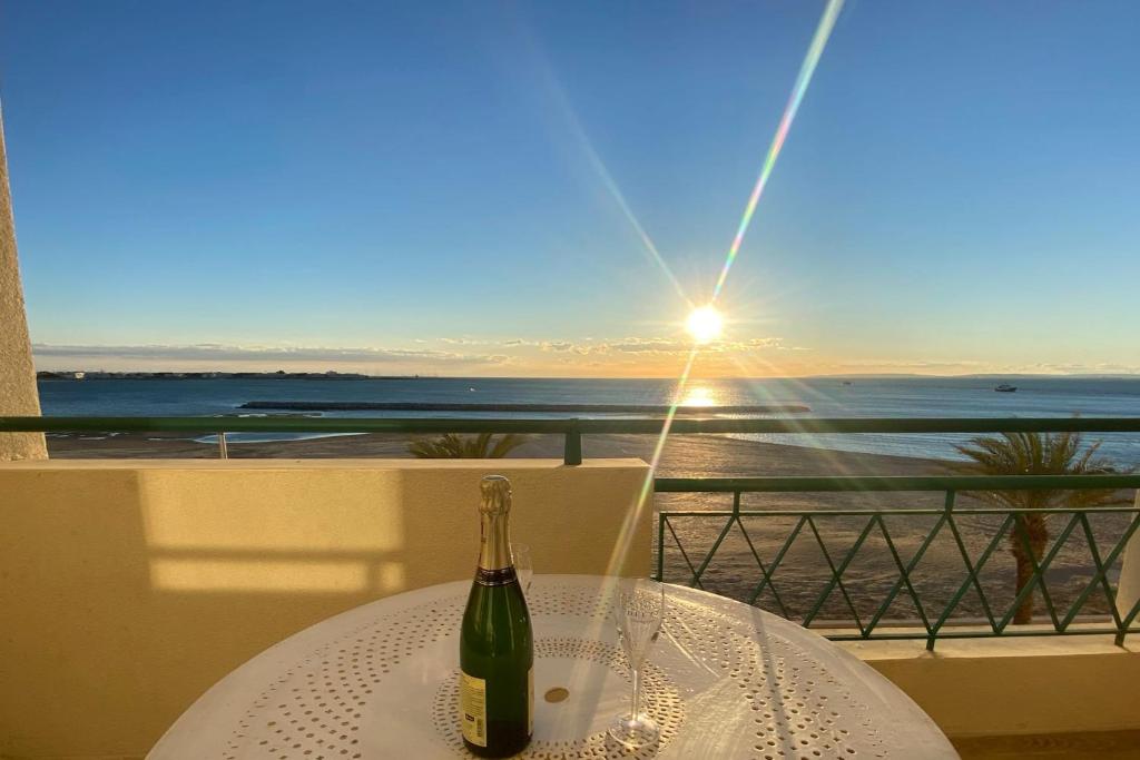 - une bouteille de vin assise sur une table avec vue sur l'océan dans l'établissement La Croix du Sud superbe appartement en duplex 2 chambres vue mer, au Grau-du-Roi