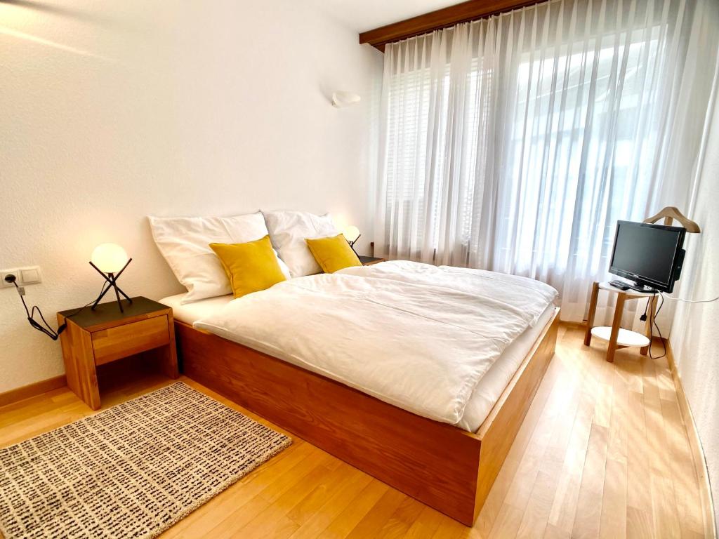 sypialnia z łóżkiem z żółtymi poduszkami i telewizorem w obiekcie Ruhiges Terrassen-Apartment mit Blick ins Grüne w mieście Dornbirn