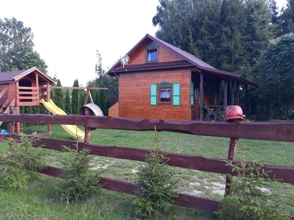 ein kleines Holzhaus mit einem Spielplatz auf dem Feld in der Unterkunft W Krainie Okiennic in Trześcianka