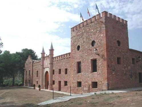 a large brick building with a fence in front of it at Masía de San Juan - Casas rurales con piscina en masía fortificada in Segorbe