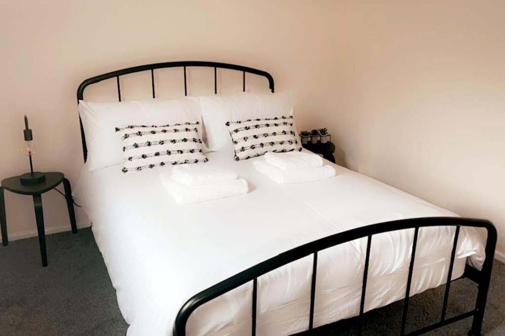 een bed met witte lakens en kussens in een kamer bij Lovely 1 bedroom studio apartment - Merthyr Tydfil in Merthyr Tydfil