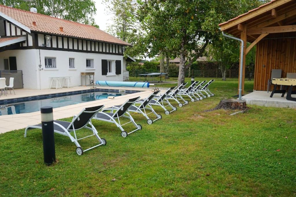 una fila de sillas sentadas junto a una piscina en Villa de 6 chambres avec piscine privee jardin clos et wifi a Sainte Eulalie en Born, en Sainte-Eulalie-en-Born