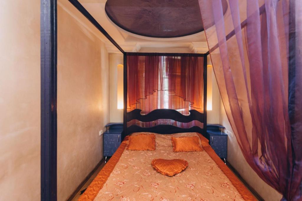 ein kleines Bett in einem kleinen Zimmer mit Vorhängen in der Unterkunft Перекопская центр люкс квартира посуточно почасово in Sumy