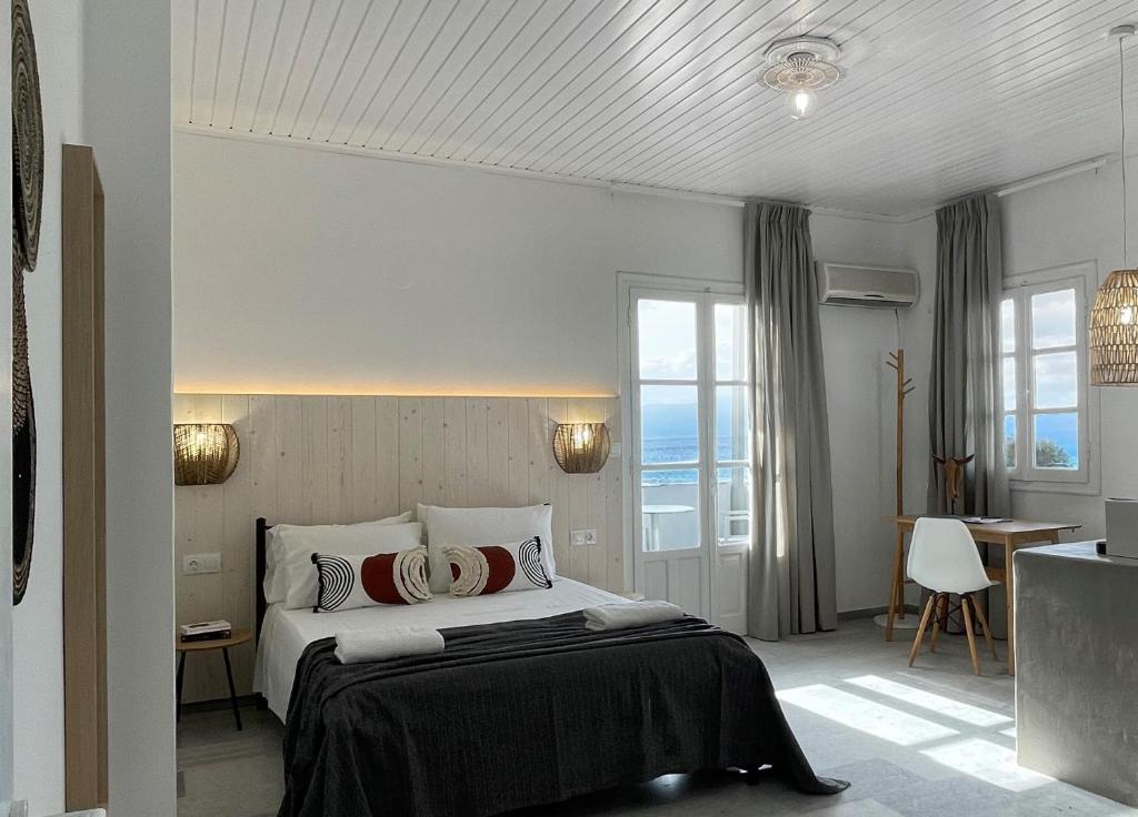 a hotel room with a bed and a desk and windows at Thalassa Naxos in Kastraki Naxou