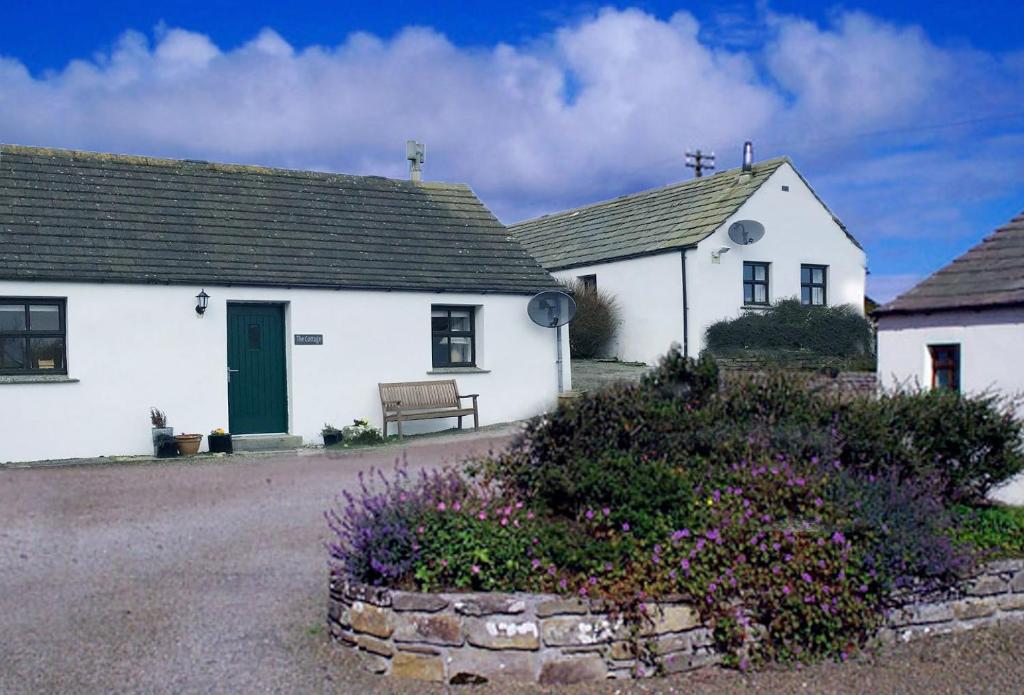 ein weißes Haus mit einer grünen Tür und einer Bank in der Unterkunft Eviedale Cottages in Evie