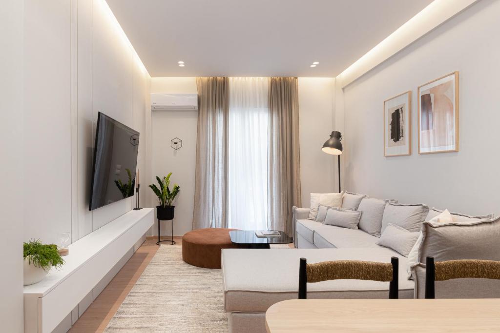 a living room with a white couch and a tv at Acropolis White Key Residence in Athens