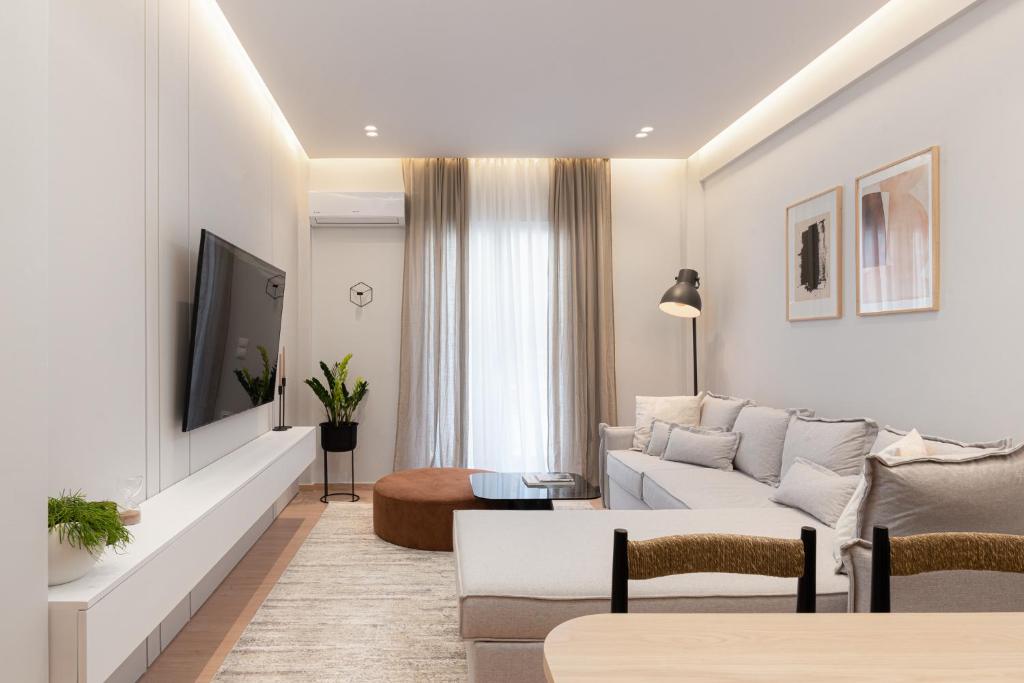 een woonkamer met een witte bank en een tv bij Acropolis White Key Residence in Athene