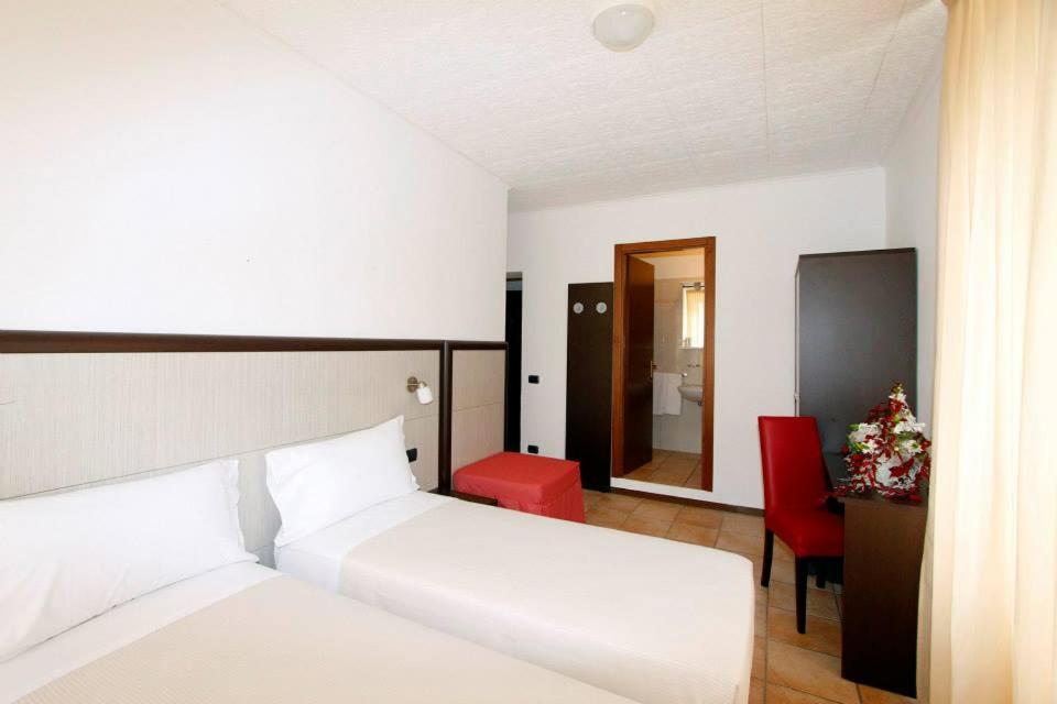 a bedroom with a white bed and a red chair at Albergo Maccagno in Maccagno Inferiore
