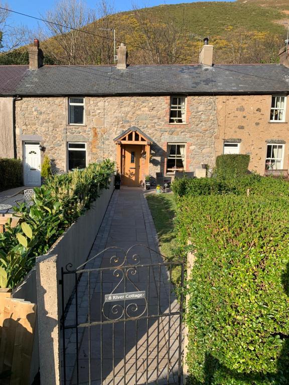 una casa de piedra con una puerta delante de ella en River Cottage, en Conwy