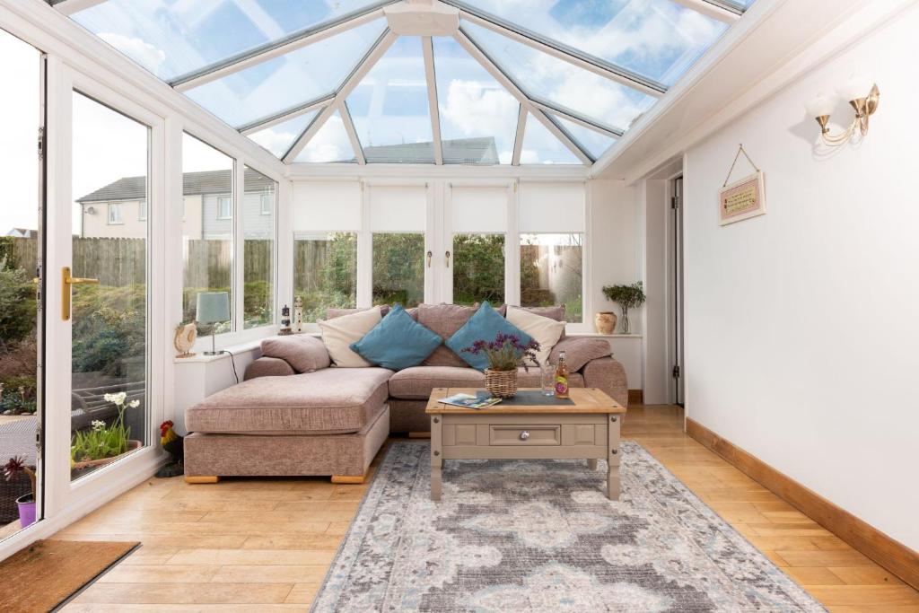 a conservatory with a couch and a table at Driftwood, Carbis Bay in Carbis Bay